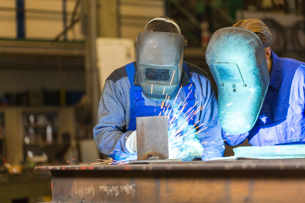 Two steel construction workers welding metal in workshop